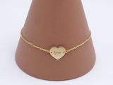 the gold heart bracelet is on a brown cone with a gold chain