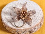 a silver ring with a flower on it sitting on a piece of wood