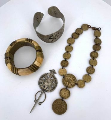 two pieces of jewelry sitting on top of a table next to a pair of scissors