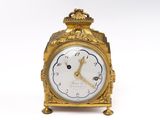 une horloge en or posée sur une surface blanche