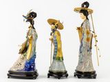 three asian figurines of women with hats and holding umbrellas
