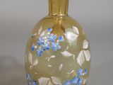 a glass vase with blue flowers on it sitting on a table