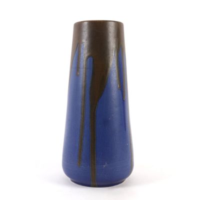 un vase bleu présentant des stries noires sur un fond blanc