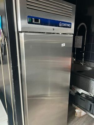 un réfrigérateur en acier inoxydable dans une cuisine, avec une étiquette bleue sur la porte