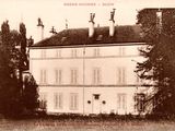 une vieille photo d'un grand bâtiment blanc avec une horloge sur la façade