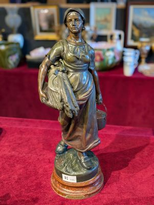une statue représentant une femme tenant un panier posé sur une table