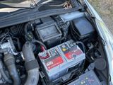 the engine of a car with its hood open and a car battery in the trunk