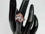 une main noire ornée d'une bague rose et blanche