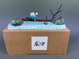 a figurine of a man sitting on a tree branch in a box