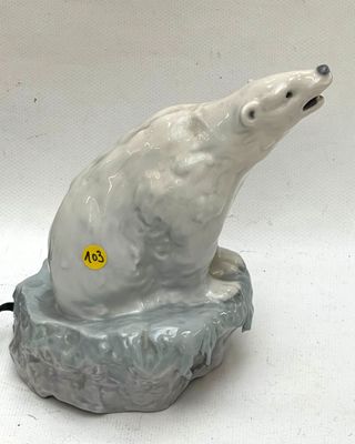 a ceramic polar bear sitting on a rock on a white background