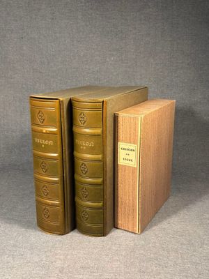 two old books sitting on top of each other on a gray surface
