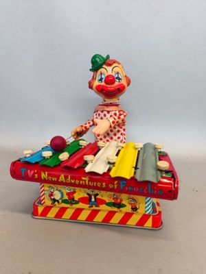 un clown en jouet assis sur une boîte à musique, tenant un instrument de musique