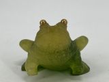 a small green frog figurine sitting on a white surface