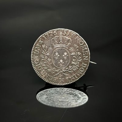 une vieille pièce d'argent posée sur une table, à côté d'un miroir