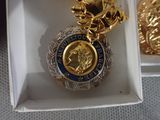 a gold and blue medal in a white box