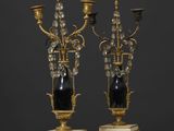 une paire de chandeliers noirs et dorés sur des socles en marbre