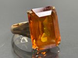 une image représentant une bague ornée d'une pierre orange sur un fond noir