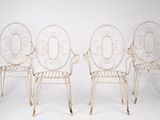 three white wrought chairs sitting next to each other on a white surface