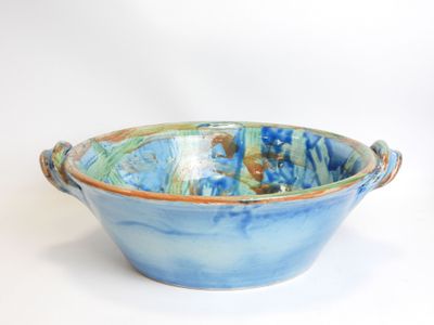 a blue and green bowl with handles on a white surface
