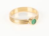 gros plan d'une bague en or avec une pierre verte