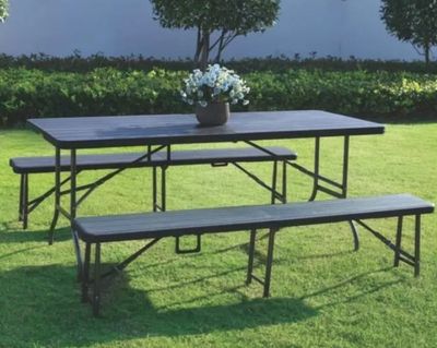une table et des bancs posés dans l'herbe, sur lesquels trône un vase de fleurs
