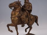 bronze statue of a man riding a horse on a wooden base