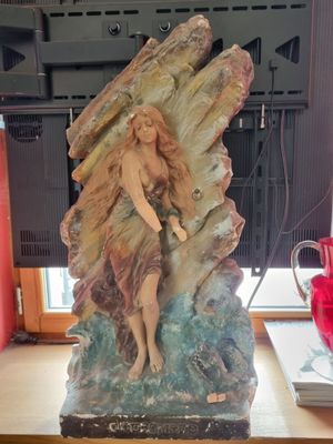a statue of a woman sitting on a rock on a desk