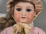 a doll that is wearing a hat and holding a flower