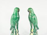une paire de perroquets en céramique verts, perchés sur une souche d'arbre
