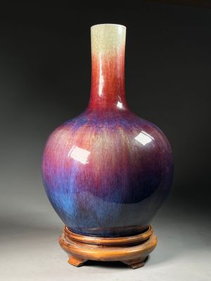 a purple and blue vase sitting on a wooden stand