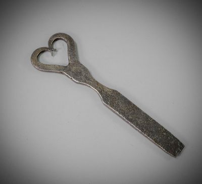 a metal spoon with a heart shaped handle on a white surface