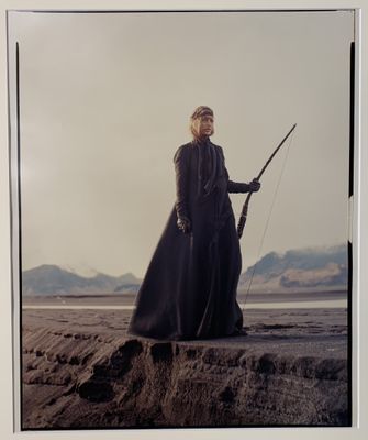 une vieille photo d'une femme vêtue d'une longue robe noire, tenant une épée