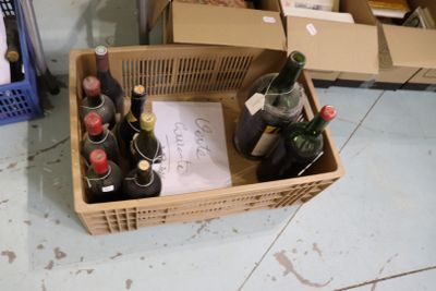de nombreuses bouteilles de vin dans un panier posé par terre