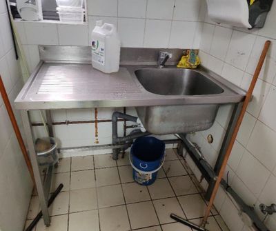 une cuisine avec un évier et un seau posé par terre