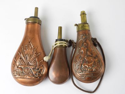 three antique brass bottle shaped like lamps on a white surface