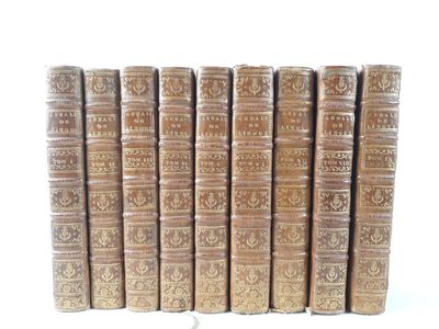 several old books are lined up in a row on a white surface