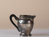 a silver pitcher sitting on a table with a brown background