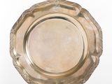 a silver plate on a stand on a white surface