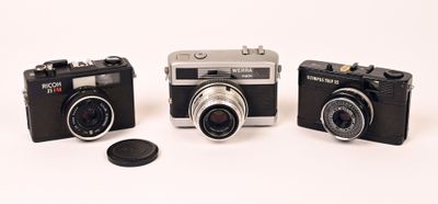 three cameras sitting next to each other on a white surface