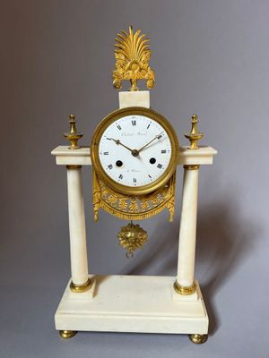 a white and gold clock sitting on top of a marble stand