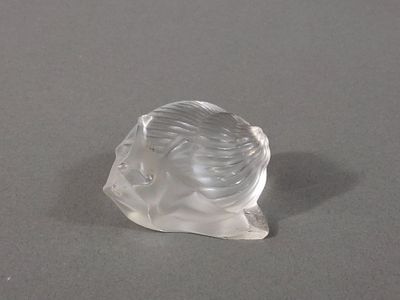 une figurine en verre transparent représentant une femme posée sur une surface grise