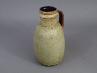 un vase marron muni d'une anse marron sur un fond gris