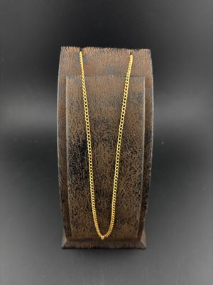 une chaîne en or sur un bracelet marron avec un fond noir