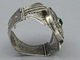 a close up of a silver bracelet with a green stone on it