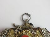 a silver purse with a red bead hanging from it