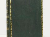 an old book sitting on top of a white table next to a white wall
