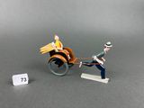 figurines of a man pulling a wooden cart with a woman in it