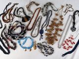 many necklaces and bracelets laid out on a bed