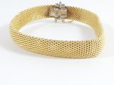 un gros plan d'un bracelet en maille dorée sur fond blanc