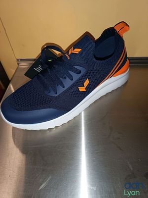 des chaussures de course bleu marine et orange posées sur une surface métallique